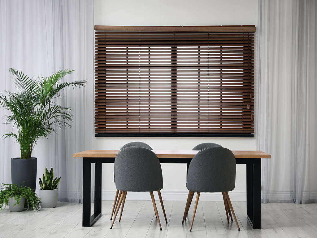 Dining room table and chairs with plants and blinds in the background